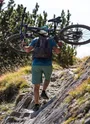Vttiste  avec son vélo sur le dos pour gravir une cote