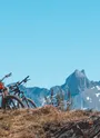 Deux amis en VTT au sommet du Mont Corbier avec les Aiguilles d'Arves en arrière-plan